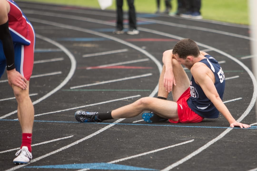 An athlete sitting on a running track, looking tired