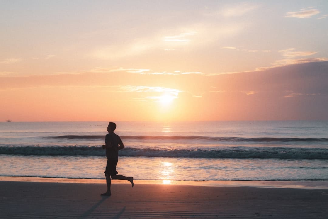Silhouette of a man walking on a beach during sunset.