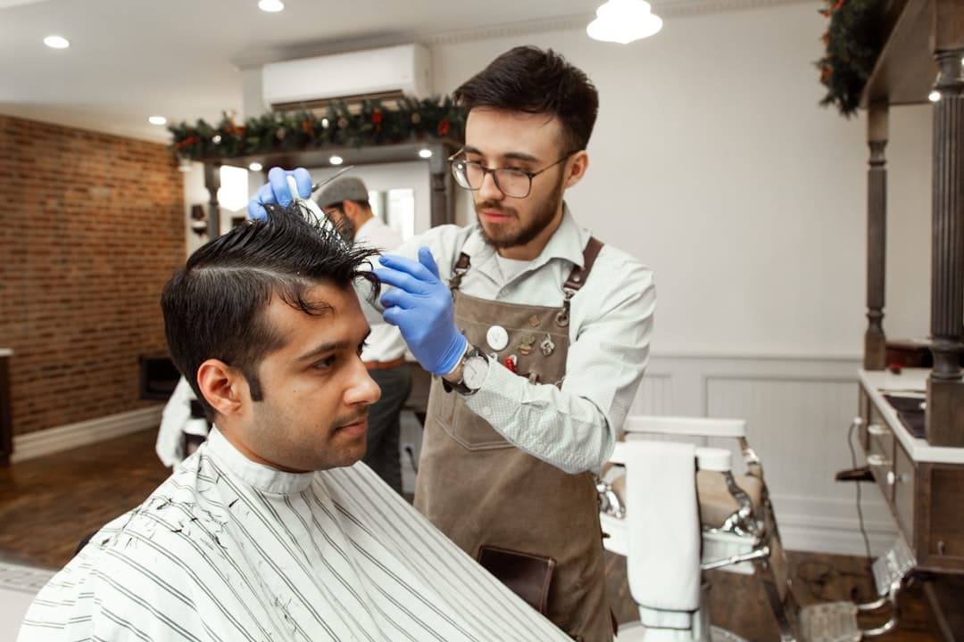 A barber styling another person's hair with clippers.