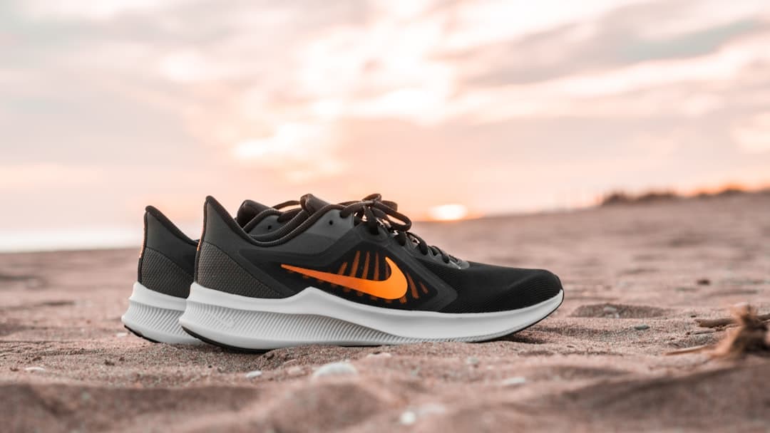 Black and white Nike athletic shoes resting on brown sand.