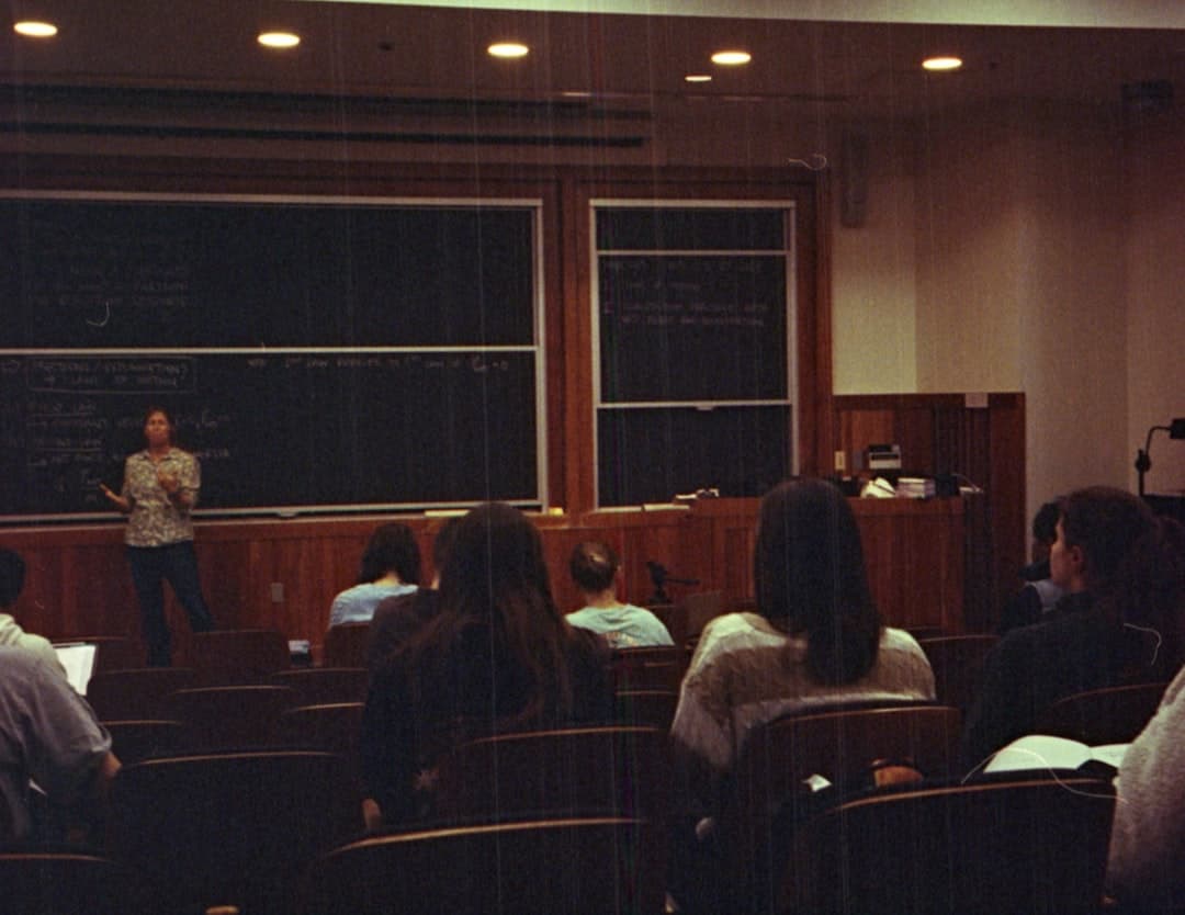 A classroom with people sitting in front of a blackboard