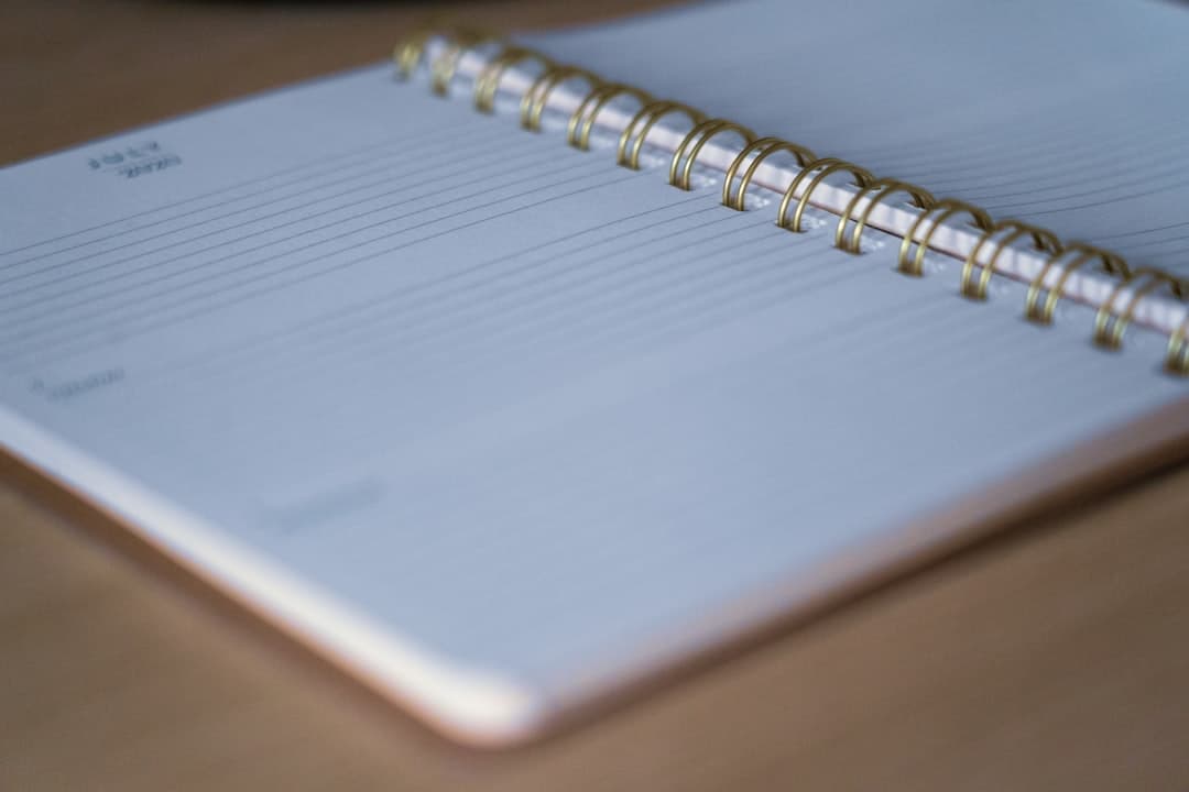 A white spiral notebook resting on a brown wooden table.