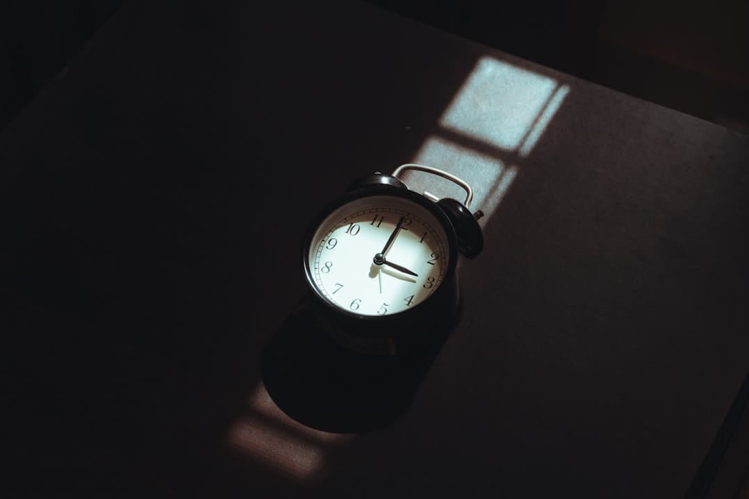 An alarm clock casting a shadow on a dark surface.